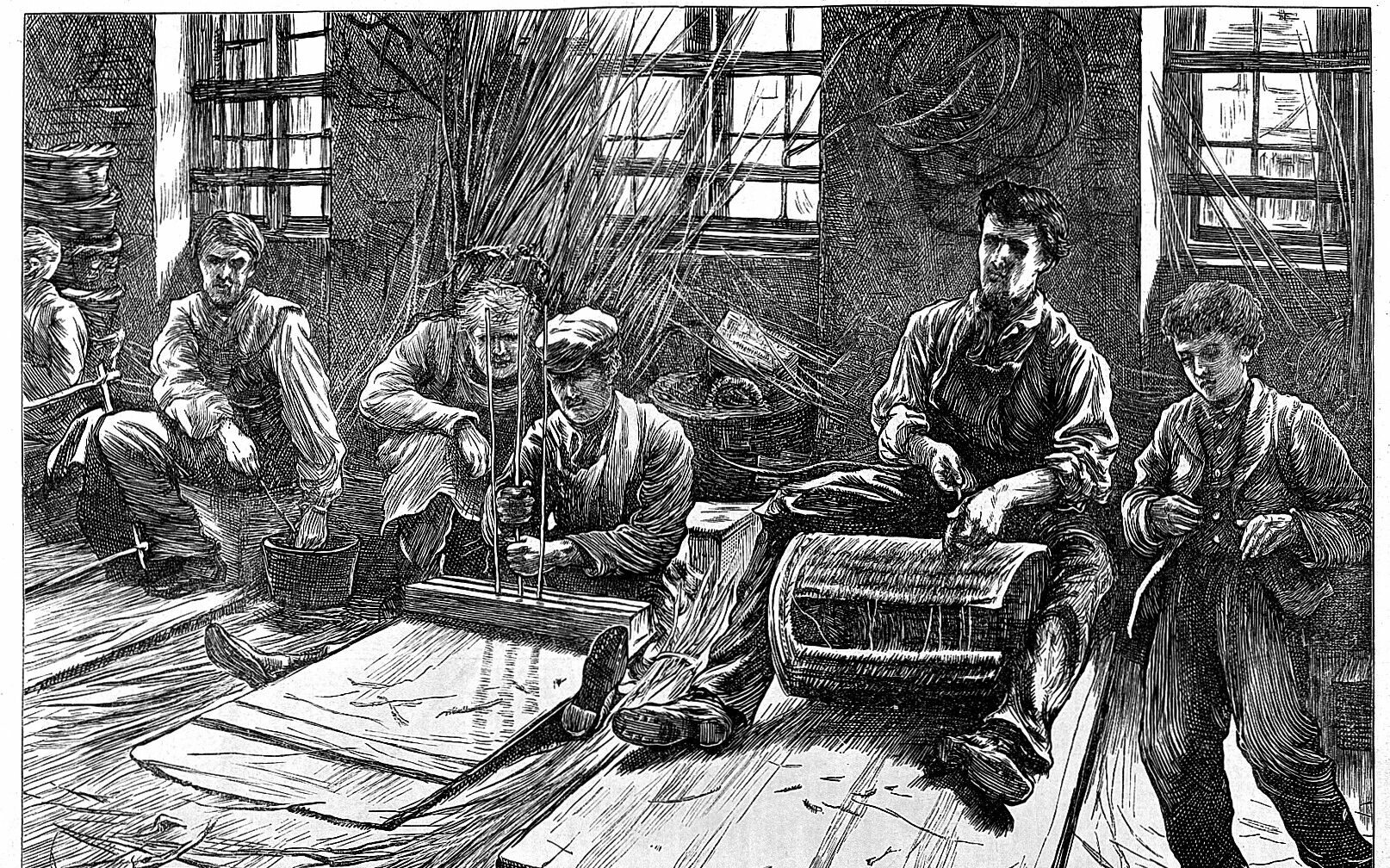 A black and white illustration of five white men of varying ages working in a production line. Four are seated and one is standing and they are surrounded by stacks and bundles of wooden sticks. A caption below reads ‘blind basket makers’.