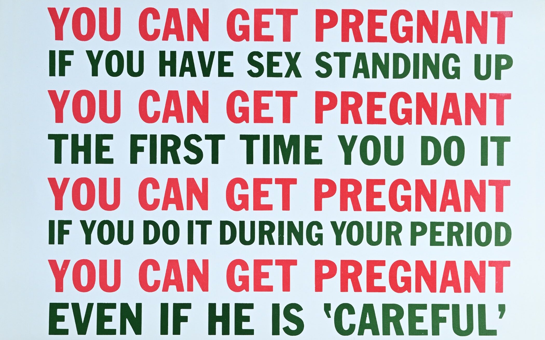 A white poster with bold red and green writing warning against the dangers of how "you can get pregnant"